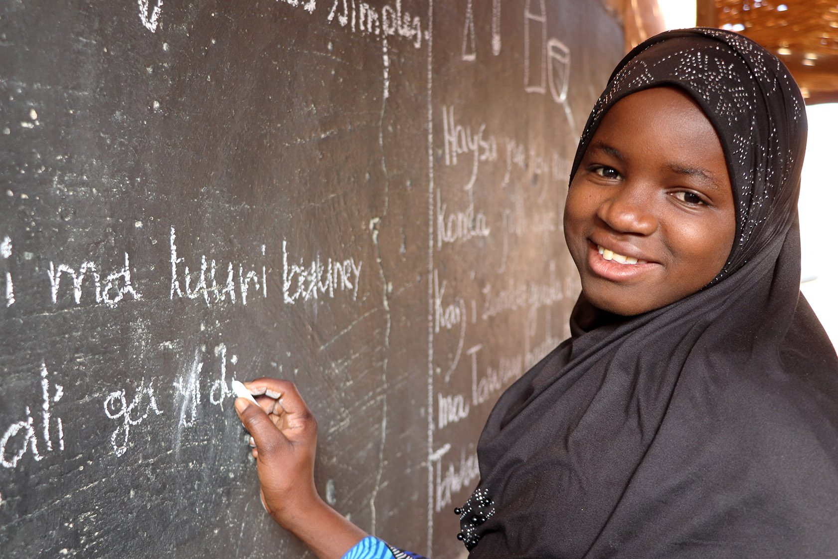 A girl writes on a chalkboard