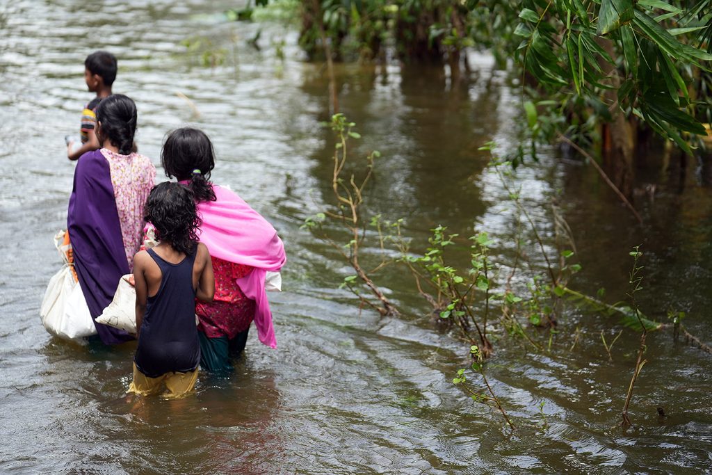 Girls wade through flooded terrain in Bangladesh